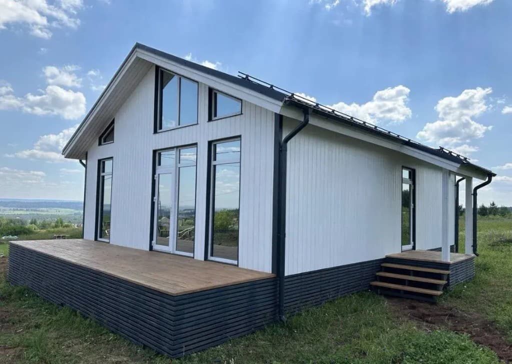Белый дом с чёрной кровлей, панорамными окнами и террасой